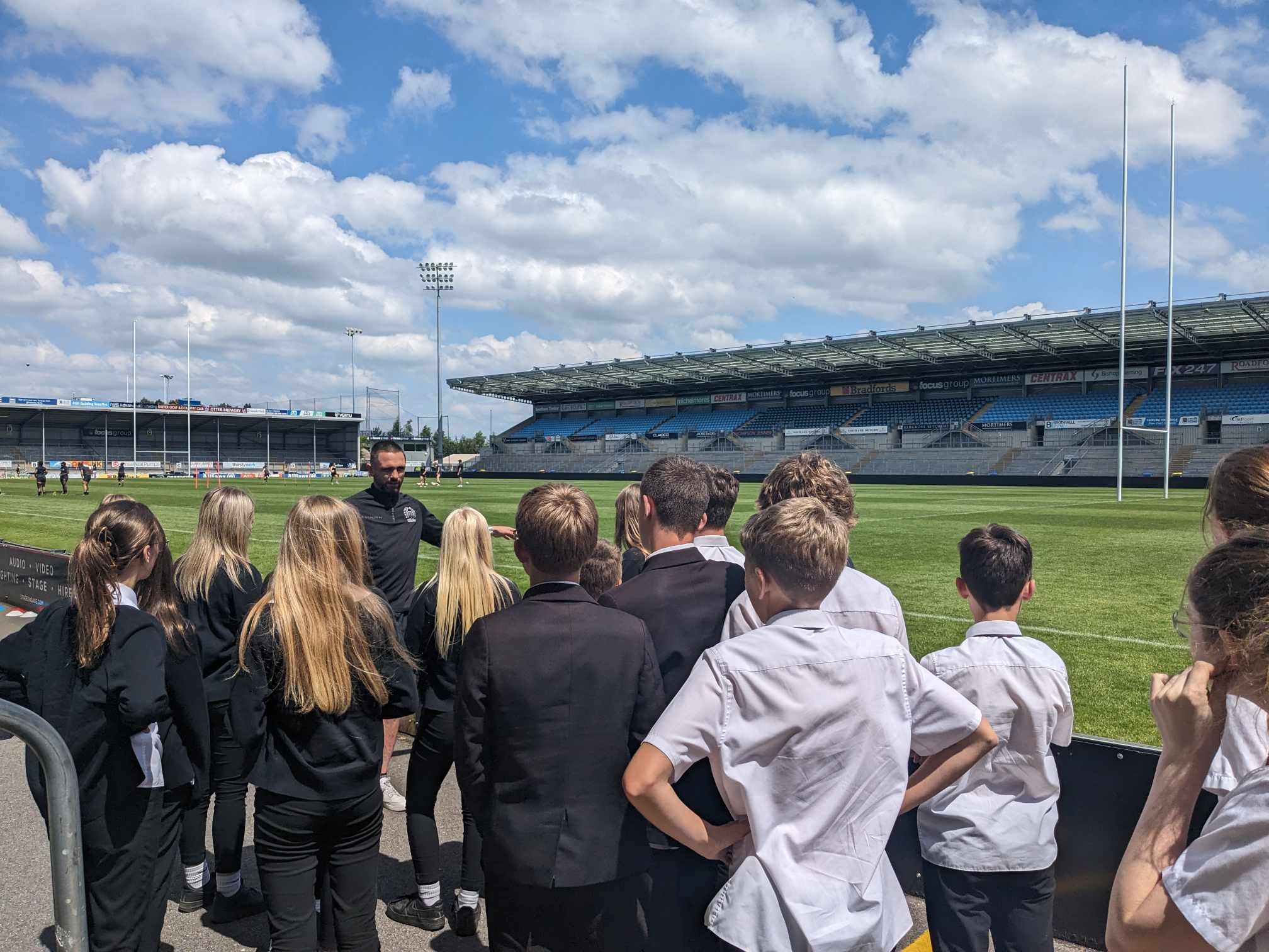Tiverton High School elite PE students completing a tour of Sandy Park home of the Exeter Chiefs. Exeter Chiefs women's team in background.