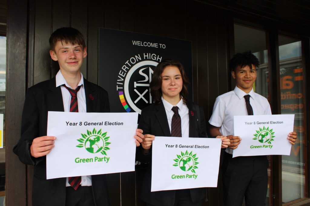 three Tiverton High School students holding Green Party banners outside of the school.