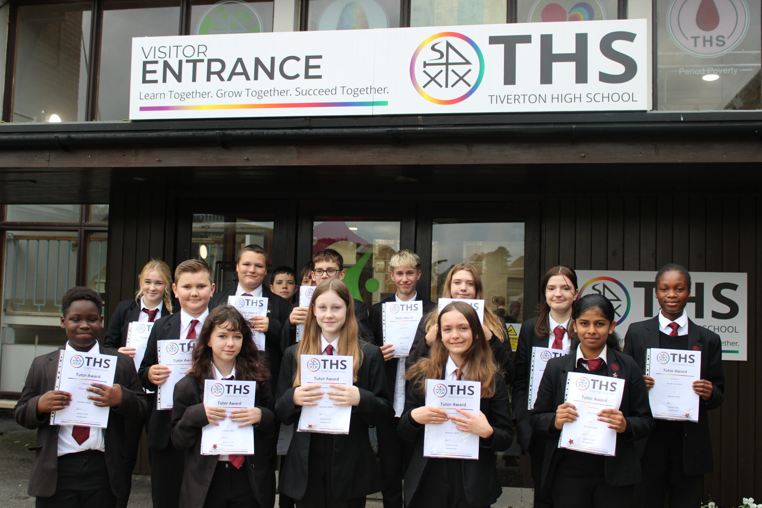 Students at Tiverton High School standing in front of the school holding their tutor award certificates.